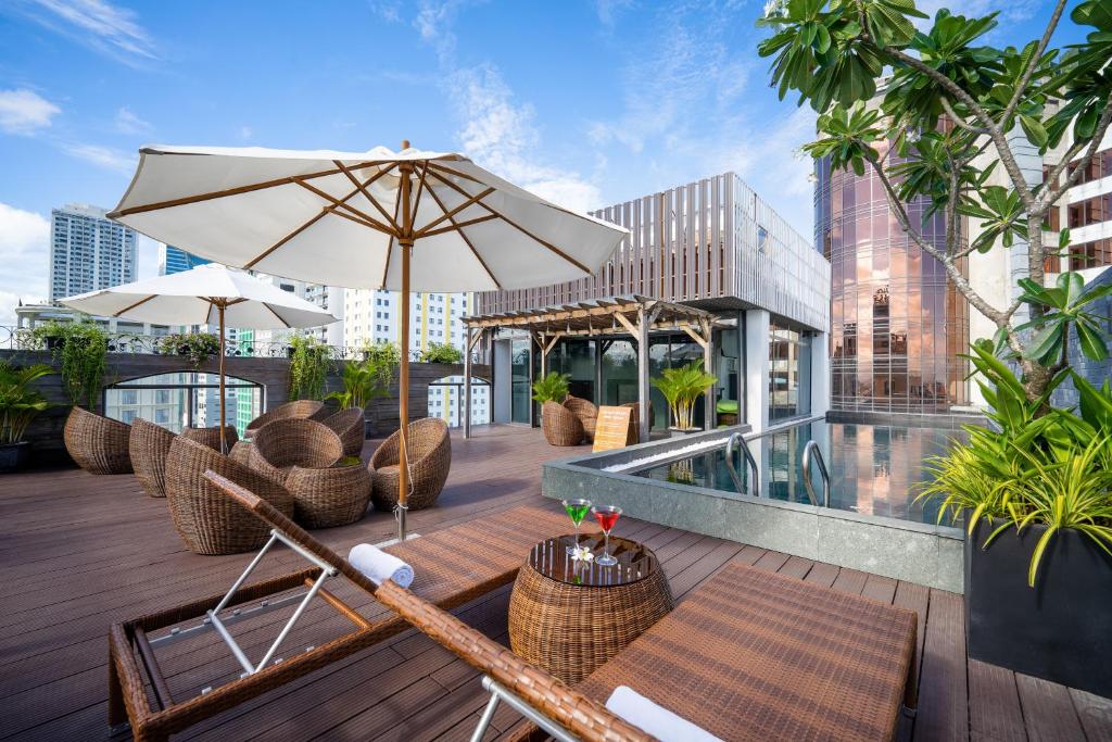 岘港Señorita Boutique Hotel的一个带椅子和遮阳伞的庭院和一个游泳池