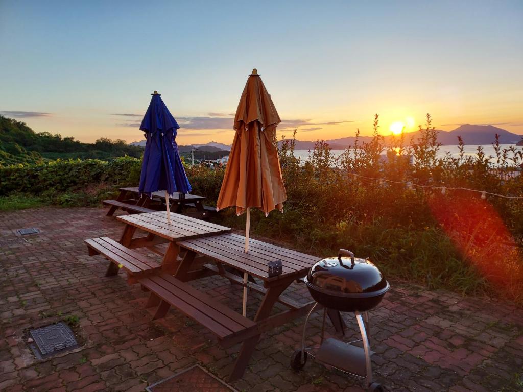 巨济Aquarius Building I 2043的两把遮阳伞和一张烧烤架,放在野餐桌上,欣赏日落美景