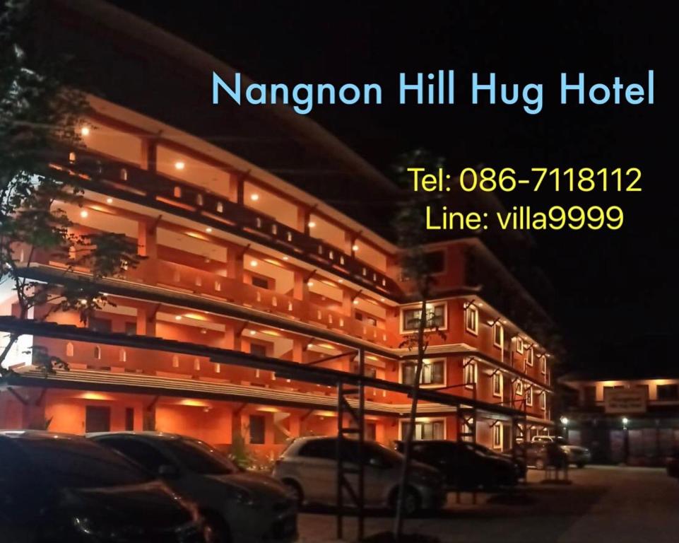 Ban Pa MuatNangnon Hill Hug Hotel的一座大型建筑,前面有汽车停放