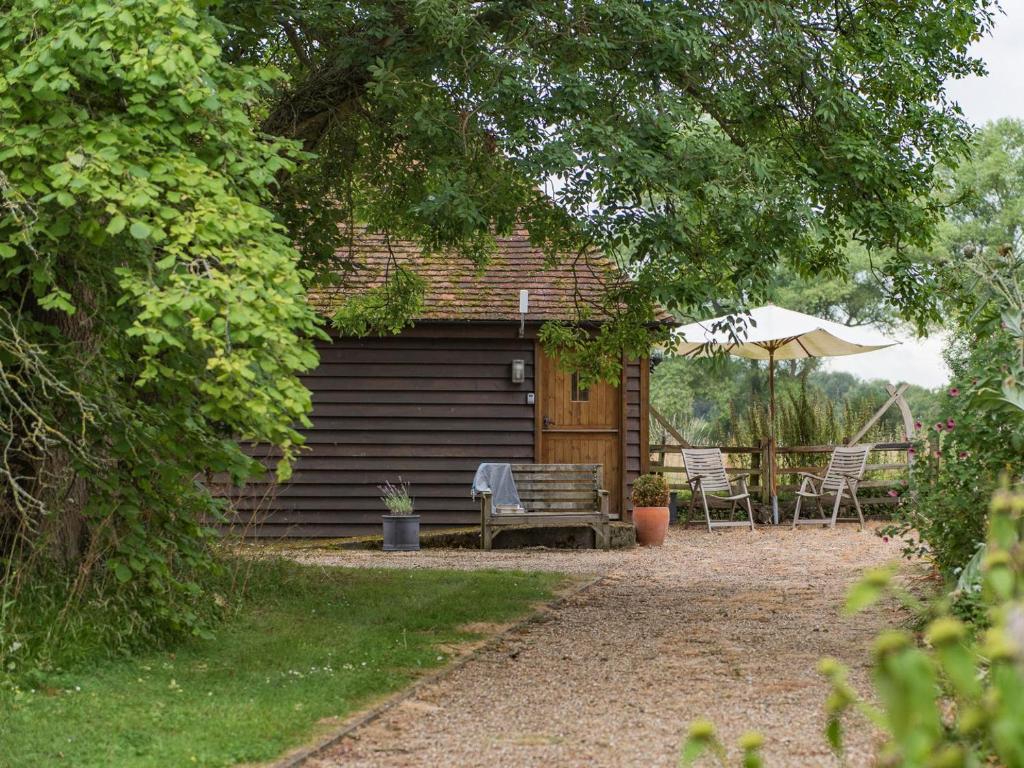 HollingbourneHeron Barn的小屋配有长凳和遮阳伞