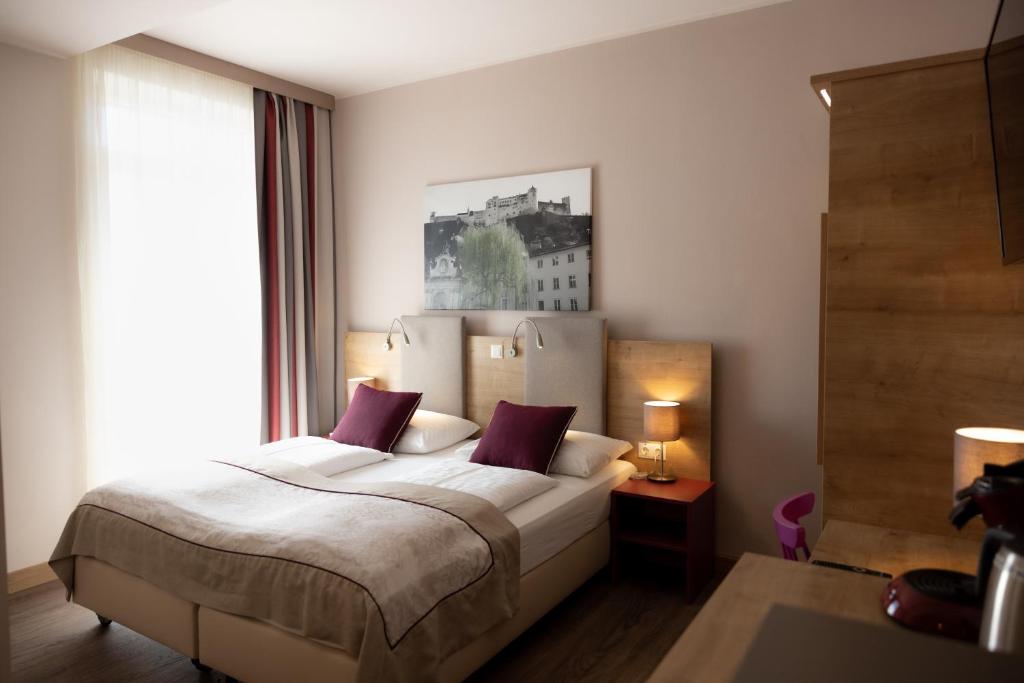 萨尔茨堡Hotel Max 70的一间卧室设有一张床和一个大窗户