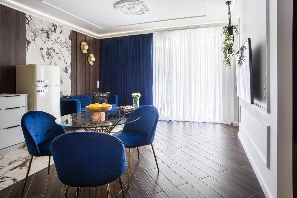 卡托维兹Luksusowy Apartament Przy Filharmonii的一间用餐室,配有蓝色的椅子和玻璃桌