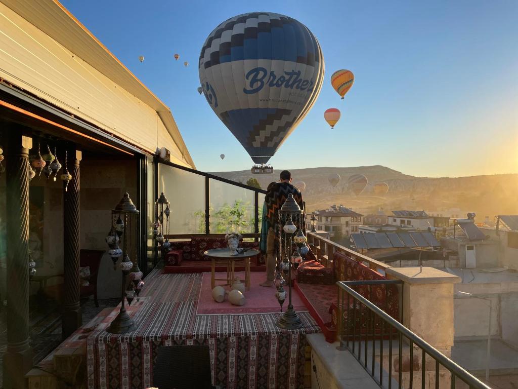格雷梅Olivia Cave Hotel的站在阳台上看热气球的人