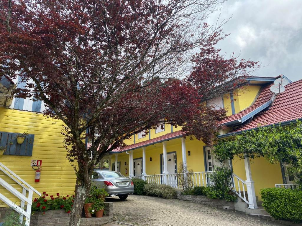 格拉玛多Apartamentos Sulla Collina Centro de Gramado localizado próximo da rua Coberta的一座黄色的房子,前面有一辆汽车