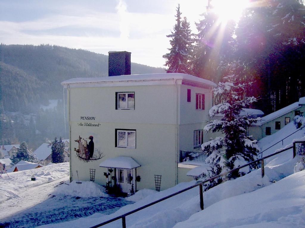 伊尔梅瑙瓦尔德兰旅馆的雪中的一个建筑,太阳在后面