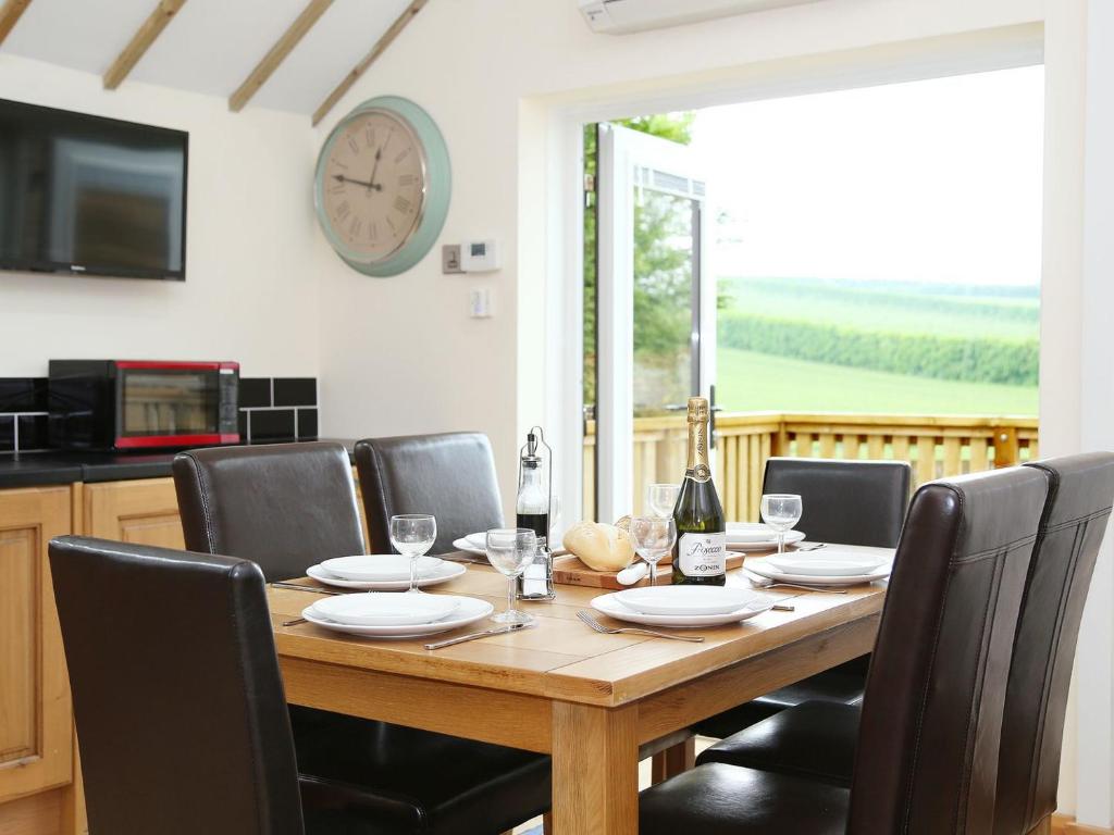 奇勒姆Kentish Barn Retreat的餐桌、椅子和墙上的时钟