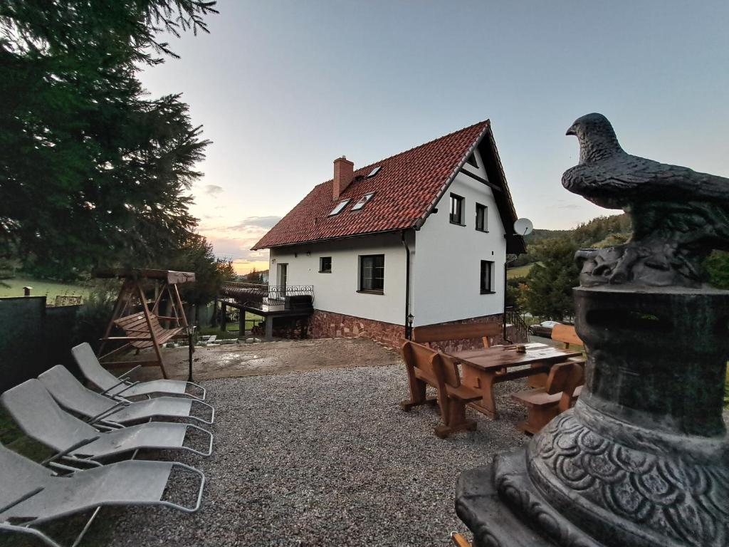 RzeczkaDom nad Potokiem Sowa的一座配有桌椅和鸟雕像的房子