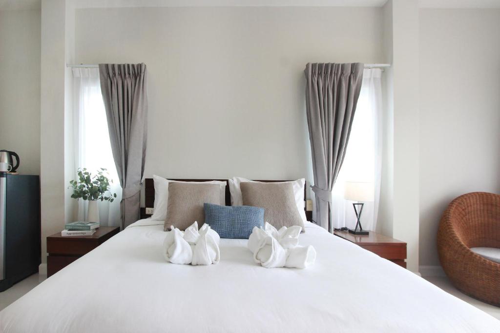 奈汉海滩The Langstan Suites的一张白色的床,上面有4双白鞋