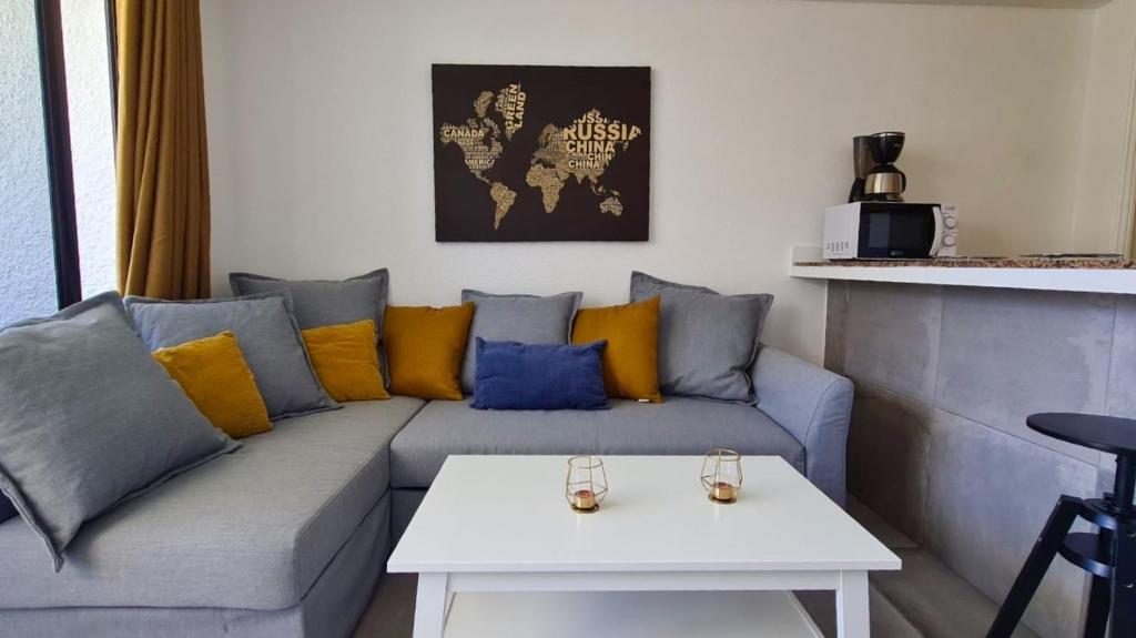 马斯帕洛马斯The SunSpot Apartment Playa del Inglés的客厅配有带黄色和蓝色枕头的灰色沙发