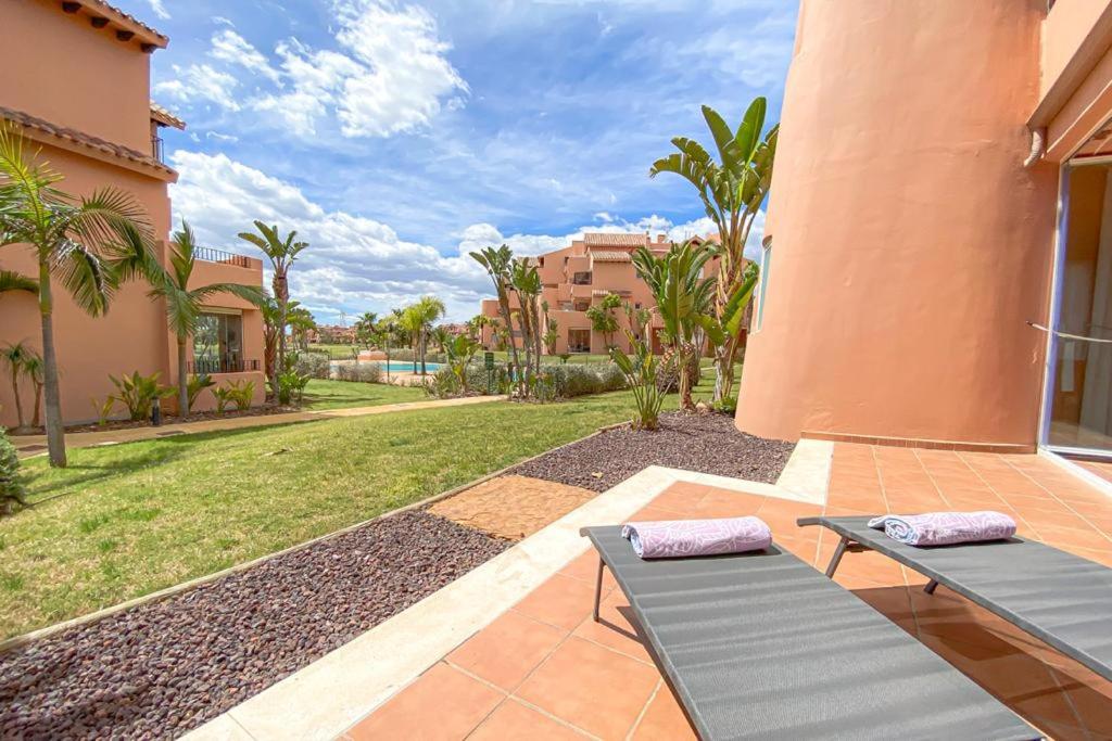 托雷帕切科Superb luxurious groundfloor 1 bedroom app on Mar Menor golf resort的庭院设有两张躺椅和一个庭院。