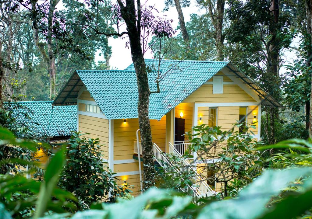 蒙纳Areva Inn Munnar by VOYE HOMES的绿色屋顶的黄色小房子
