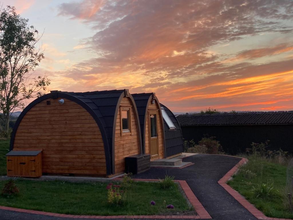 LeightonHedgehog Glamping Pod School House Farm的庭院中的一个小小屋,享有日落美景