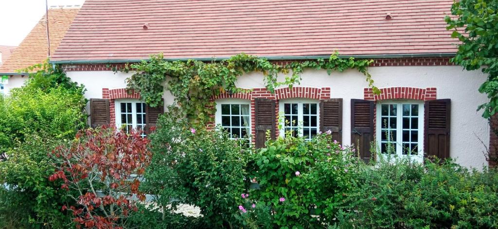 NoyersChantilly ,petit déjeuner et table d'hôtes possible的白色的房子,有红色的屋顶和灌木丛