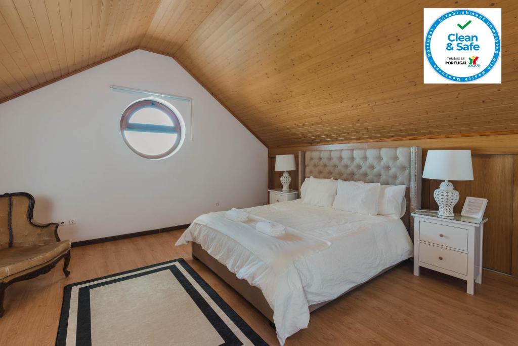 佩尼亚什达绍迪Retiro da Serra的卧室设有白色的床和木制天花板。