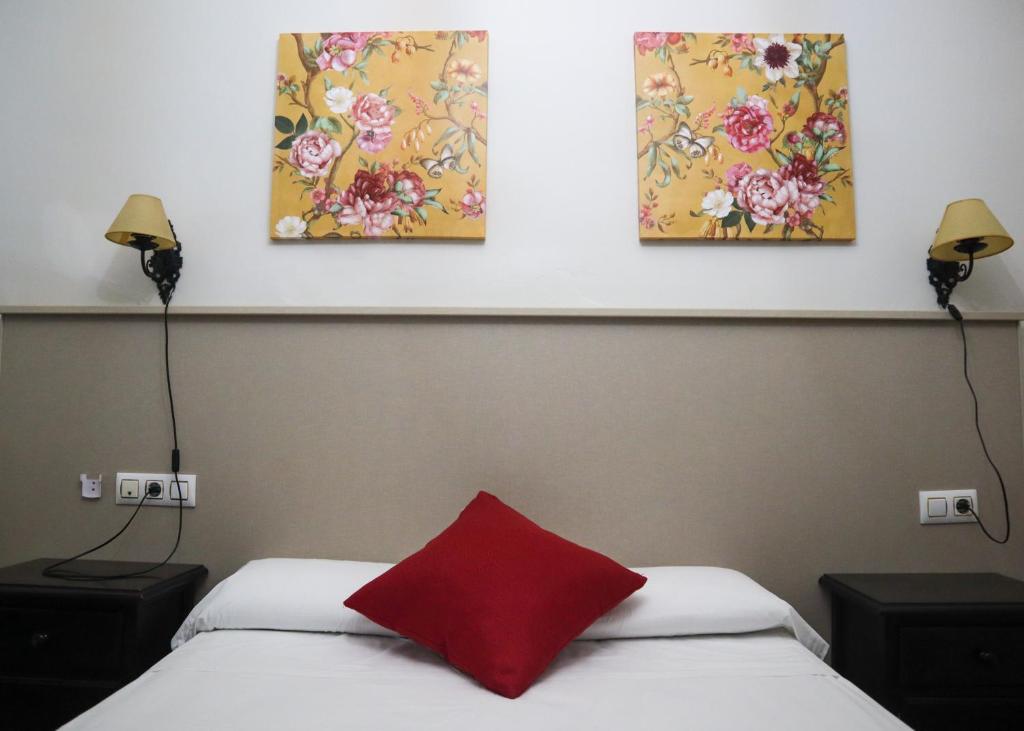 卡莫纳Apartamentos Turisticos Casa Cantillo的一间卧室配有两张床,墙上有三幅画作