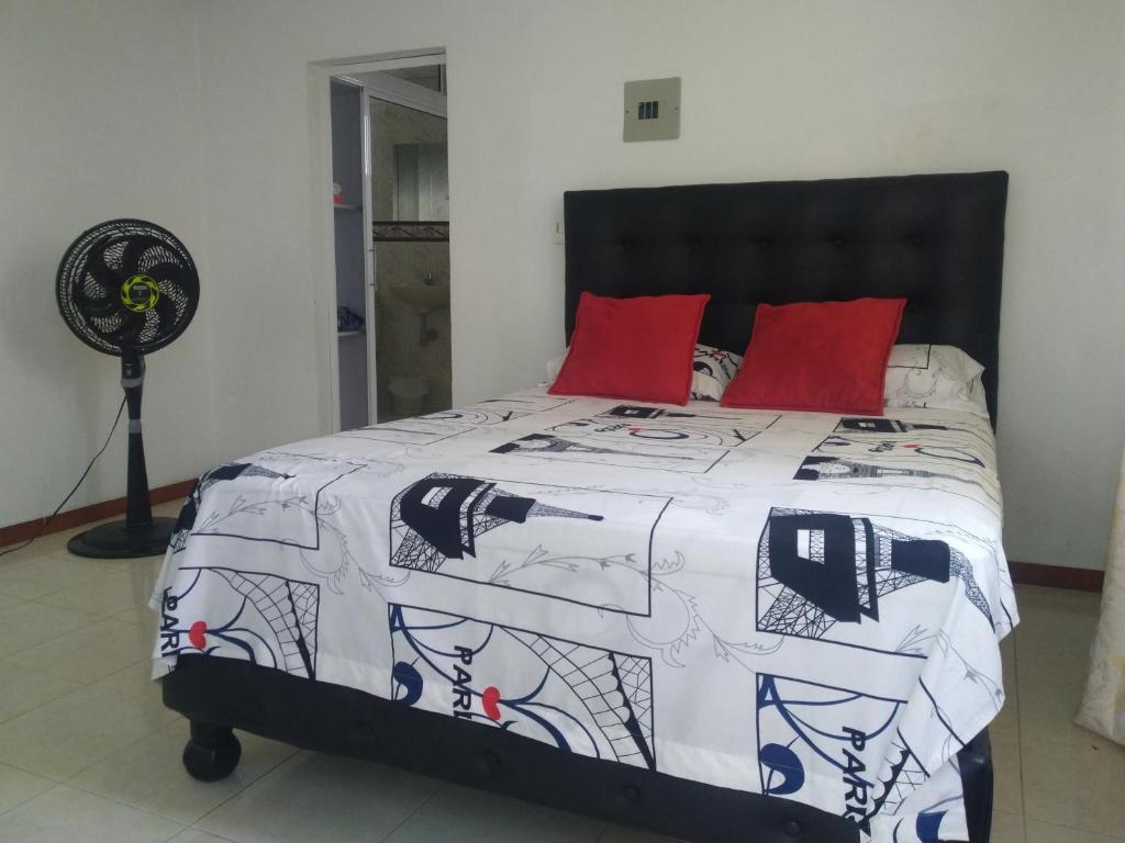 卡利Apartamento oasis del norte的一张带黑白棉被和红色枕头的床