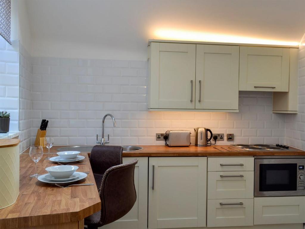 格洛索普Kinder Apartment - Uk12957的厨房配有白色橱柜和木桌