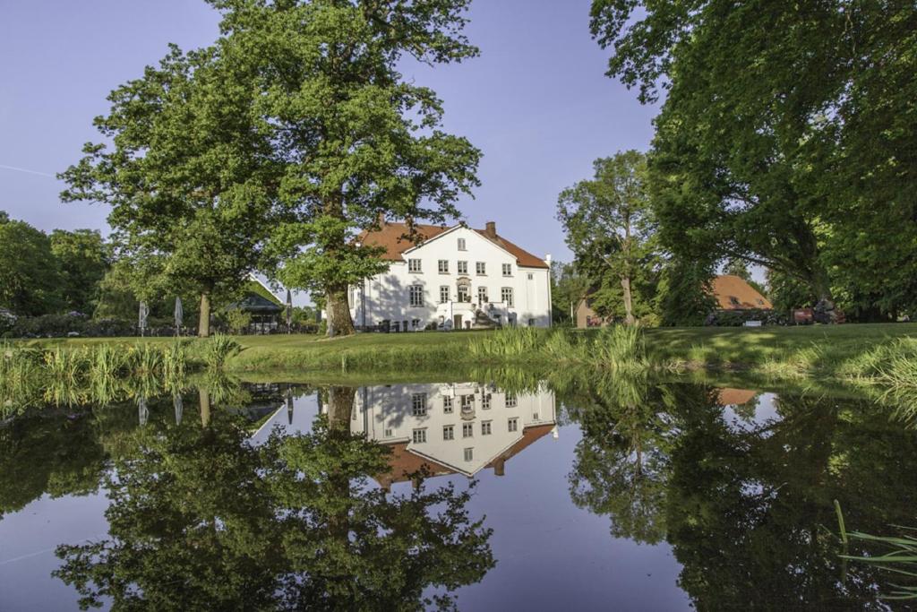 AlvesloheHotel & Gästehaus Gut Kaden的湖水中反映的房子