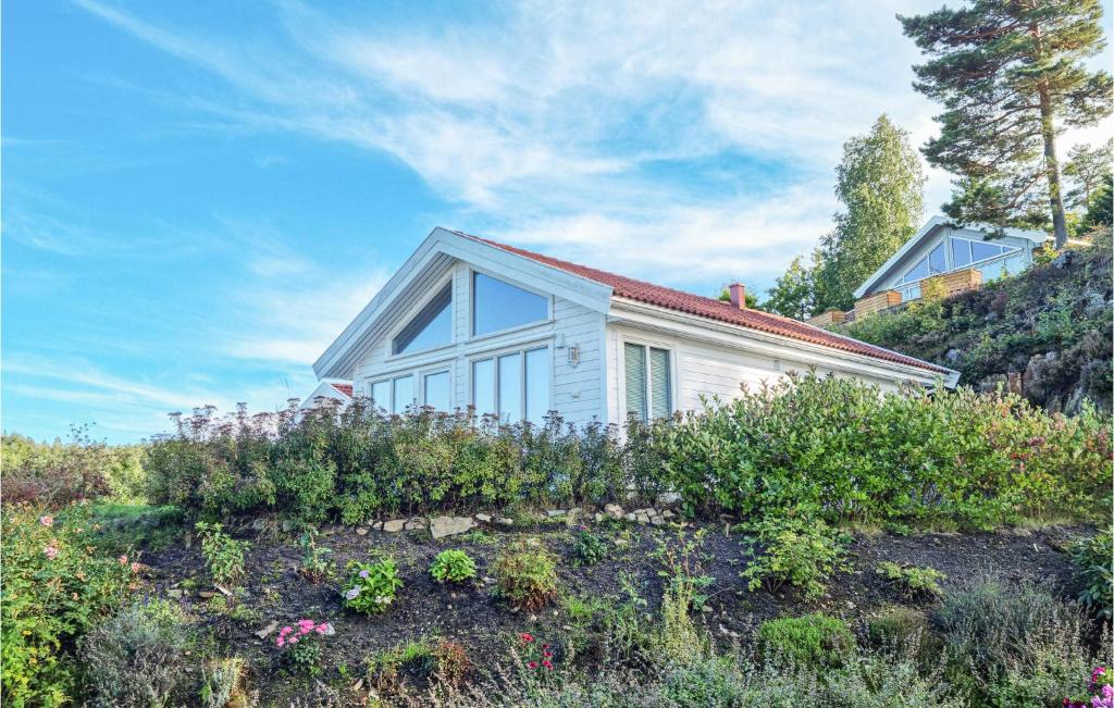 特韦德斯特兰Cozy Home In Tvedestrand With House Sea View的一座小白色房子,位于山上,种着鲜花