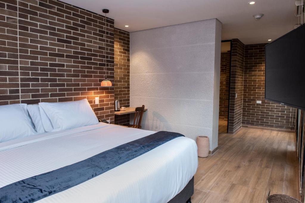 Carmen de ViboralCasa Rosé Hotel的一间卧室设有一张床和砖墙