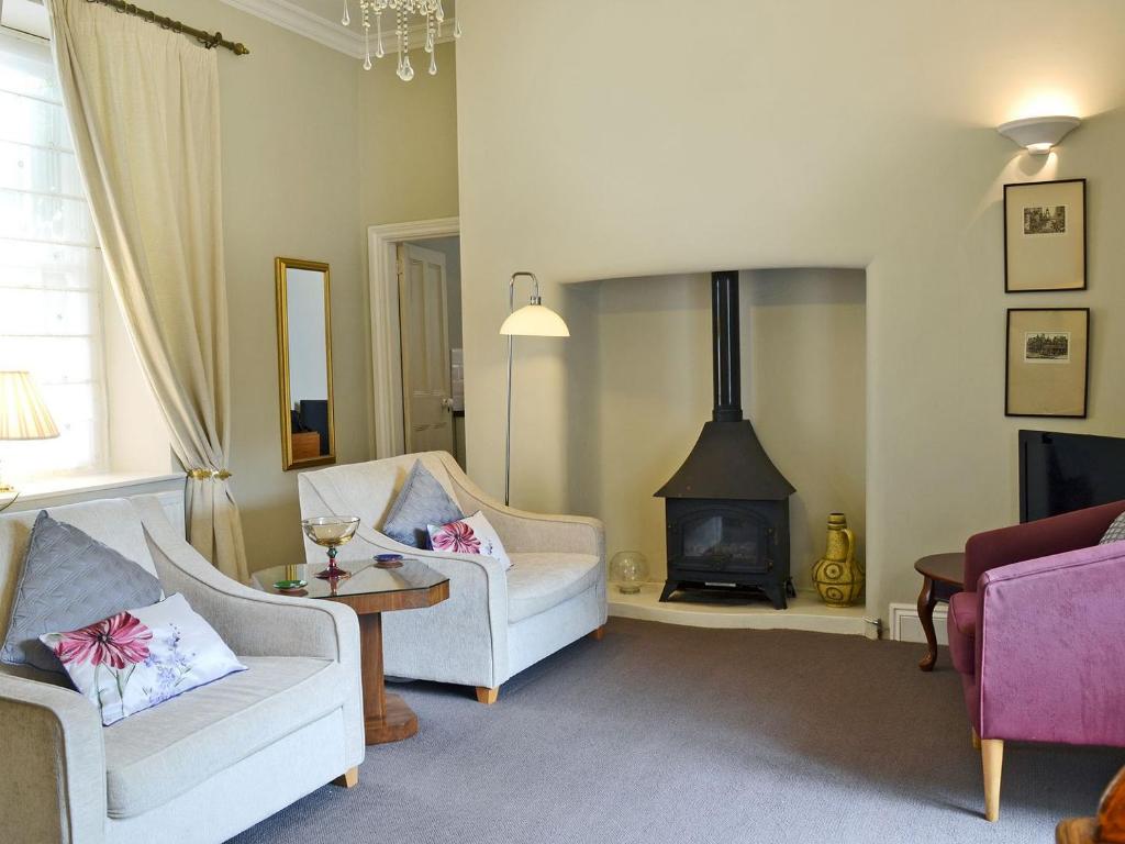 阿克斯明斯特Porters Lodge的客厅配有两把椅子和燃木炉