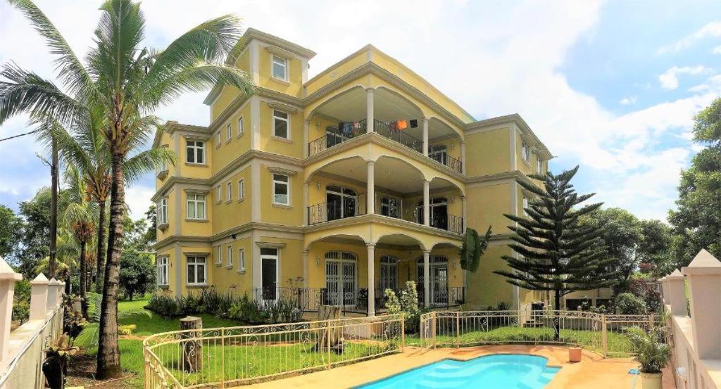 马埃堡La Maison de Bel Air的一座大型黄色房子,前面设有一个游泳池