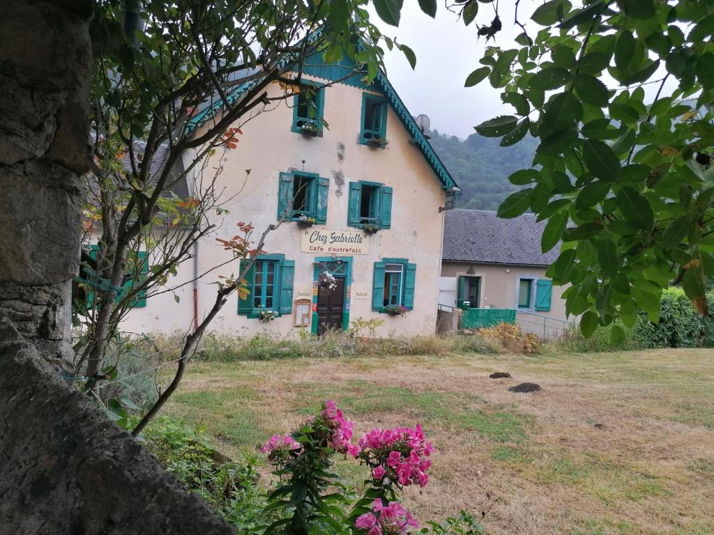 BeaudéanAuberge Chez Gabrielle - Vallée de Lesponne的一座带绿色百叶窗和鲜花的老房子