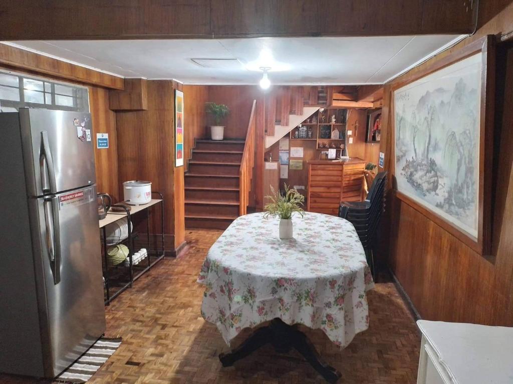 碧瑶Amara Transient House的厨房配有桌子、冰箱和楼梯。