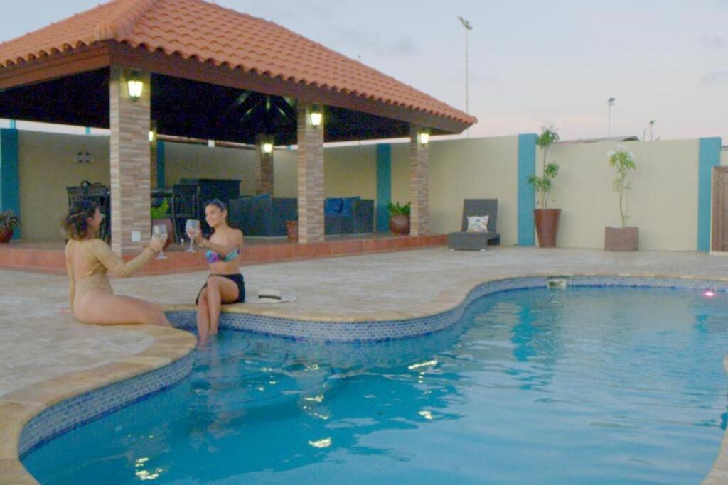 奥拉涅斯塔德Enjoyment Villa Cataleya的两个女人坐在游泳池边