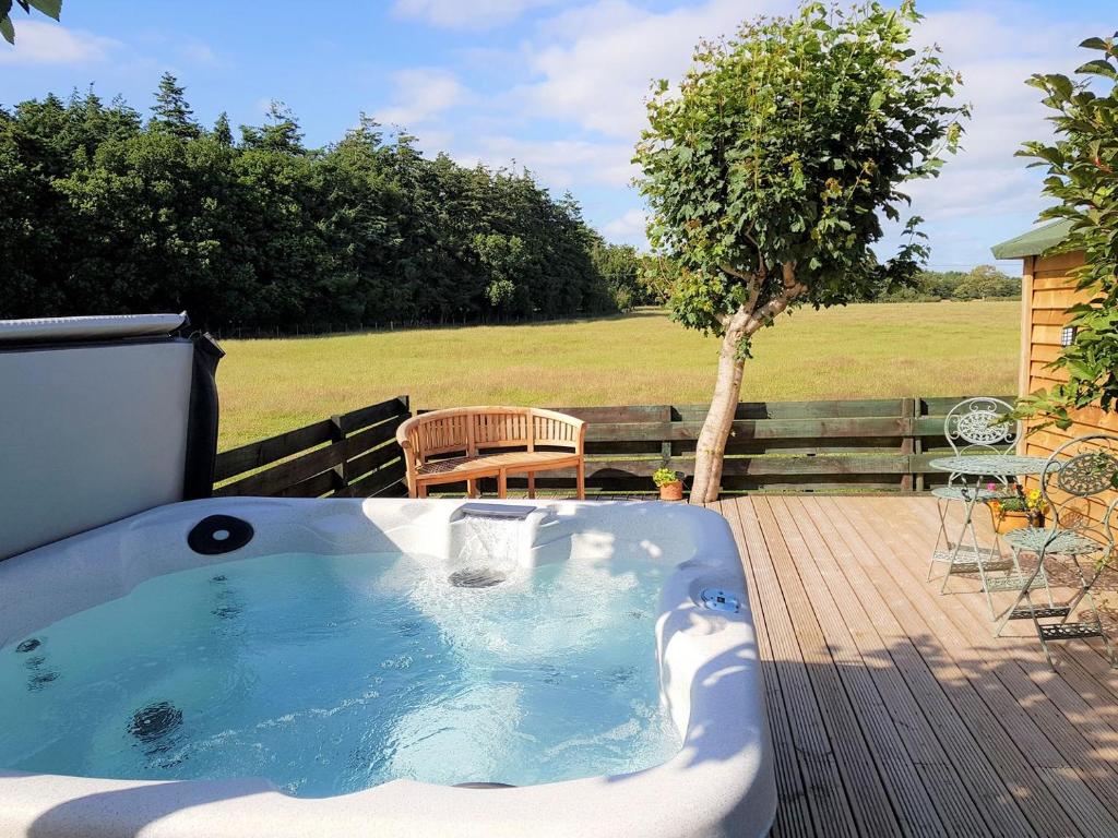 安南Trebor Cottage的甲板上的热水浴池配有桌子和长凳