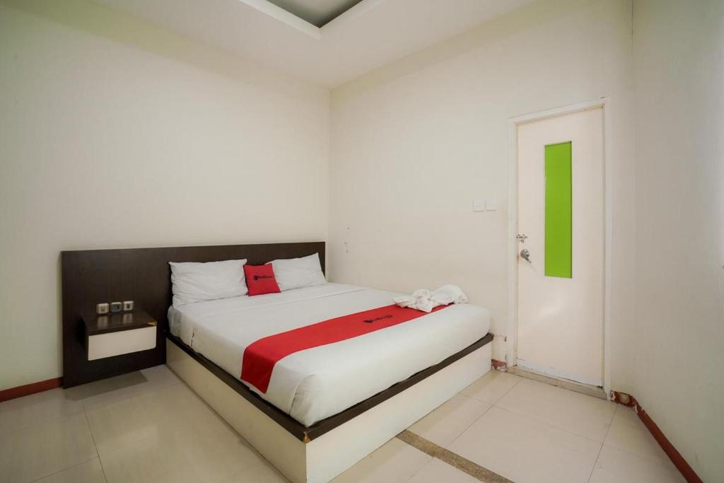纳闽巴霍RedDoorz near Pantai Pede的白色卧室配有一张带红色毯子的床