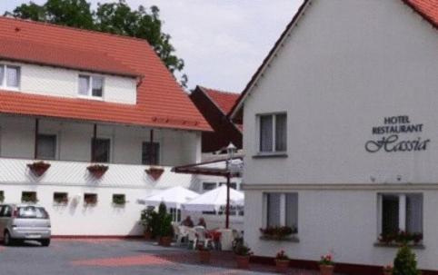 Frielendorf哈莎餐厅酒店的一座白色的建筑,有红色的屋顶,还有一座有汽车的建筑