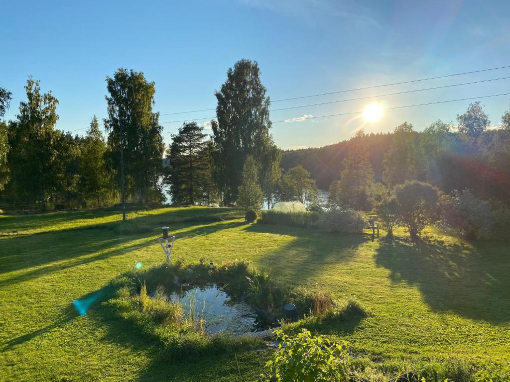 SkinnskattebergSjöutsikt, Röd trästuga med traditionellt yttre Skandinavisk, modernt inre och alla bekvämligheter, Sol hela dagen på stora altanen, Tryggt, Vinterbonat, Fiske, Båt的站在池塘的田野上的人