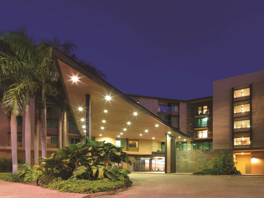 达尔文达尔文海滨阿迪娜公寓酒店的一座棕榈树和灯光的建筑