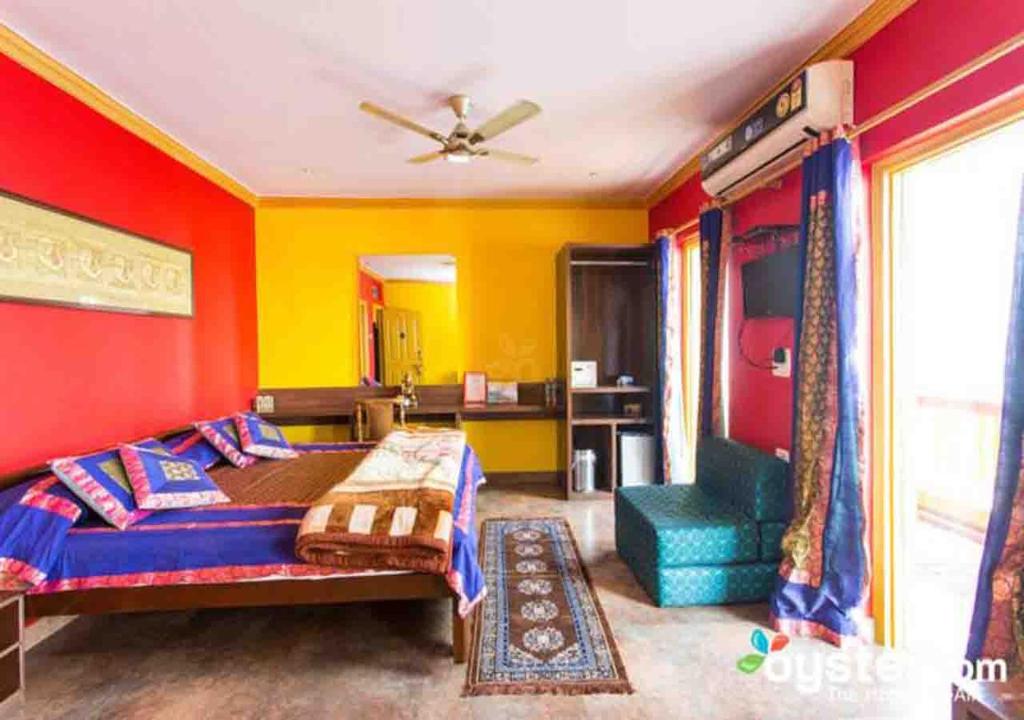 瓦拉纳西甘帕蒂酒店的一间卧室拥有红色和黄色的墙壁,配有一张床和椅子