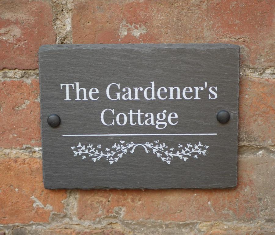莱明斯特The Gardener's Cottage的砖墙上看园丁小屋的标志