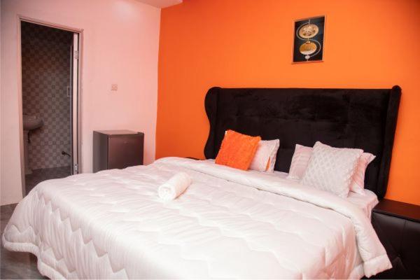 KazungulaKasbek Lodge & Tours的橙色墙壁的房间里一张大白色的床