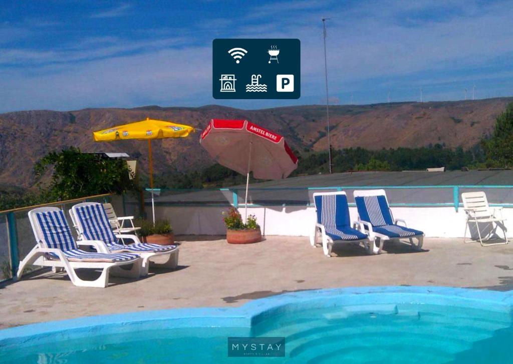瓜尔达MyStay - Quinta do Tendeiro的一组椅子和一把遮阳伞,位于游泳池旁