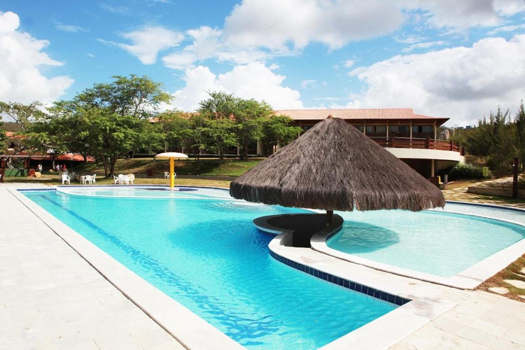 格拉瓦塔Flat Studio 11 Hotel Fazenda Gravatá-PE的一个带草伞的大型游泳池