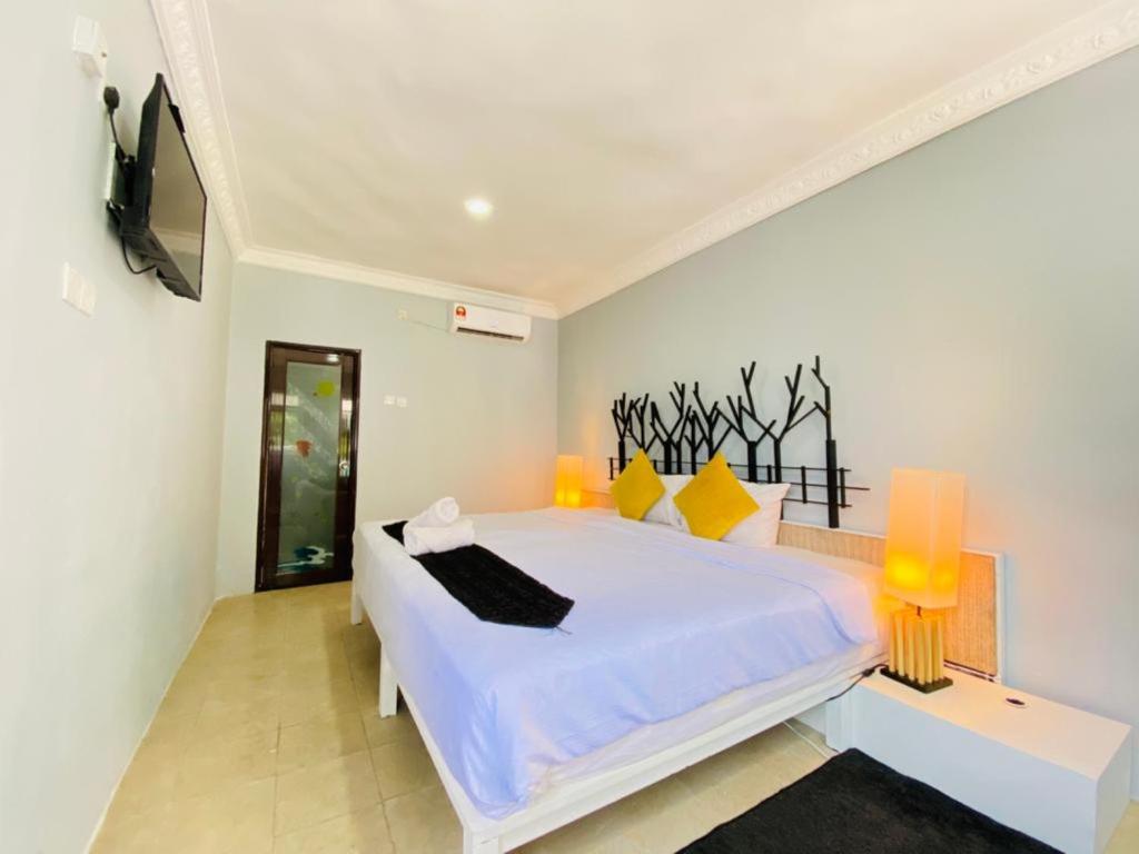 珍南海滩FAT MERMAID GUESTHOUSE的一间卧室配有一张白色大床和黄色灯。