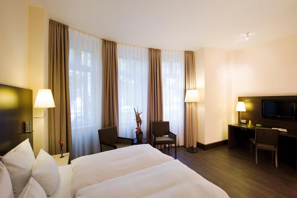 美因河畔法兰克福Villa Hotel Frankfurt by MZ HotelCollection的酒店客房设有一张白色大床和一张书桌