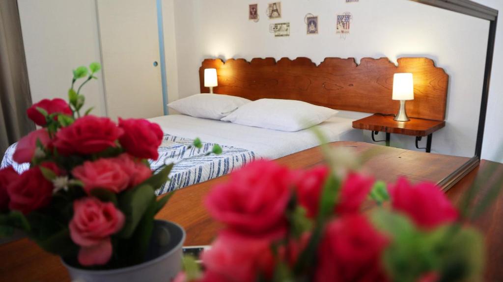 卢那欢纳Lunawasi Hospedaje的一间卧室配有一张床和一张红玫瑰桌子