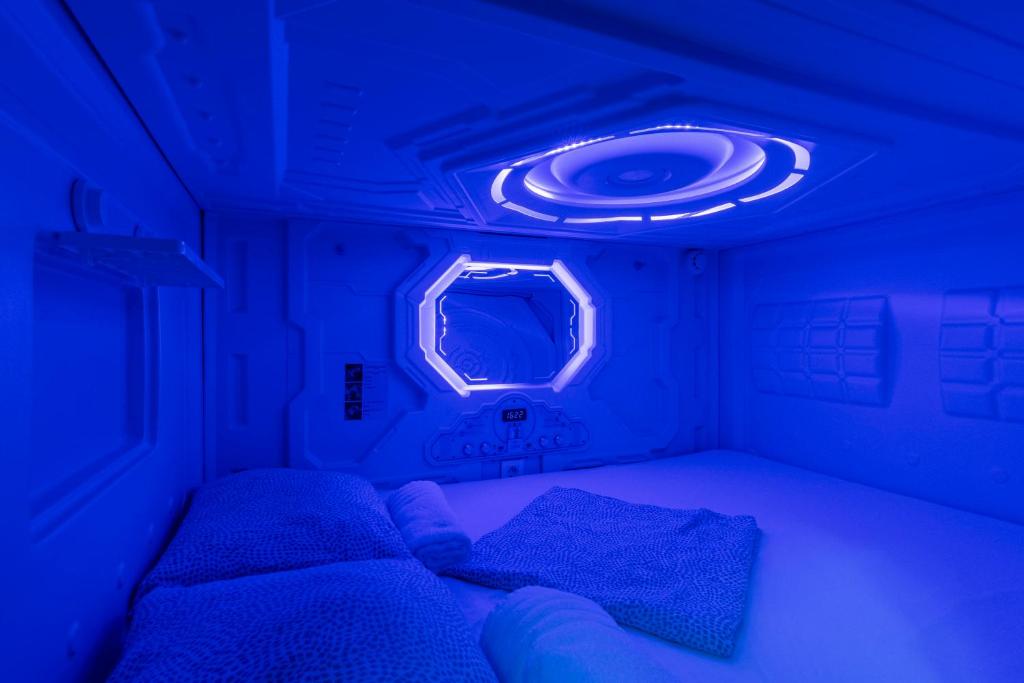 马德里OXYGEN HOSTEL Capsula的小房间设有两张床和蓝色的灯光