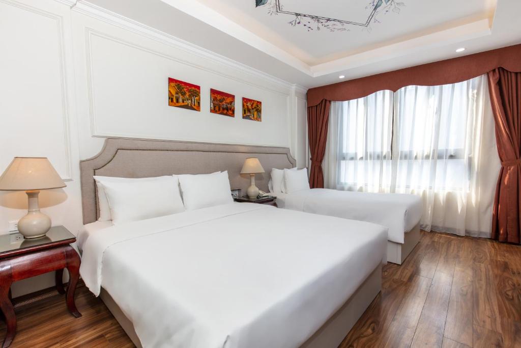 河内Golden Legend Palace Hotel的酒店客房设有两张床和窗户。