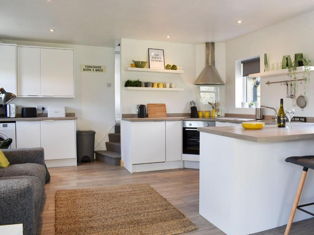 AddinghamLittle Plumtree的厨房配有白色橱柜和台面