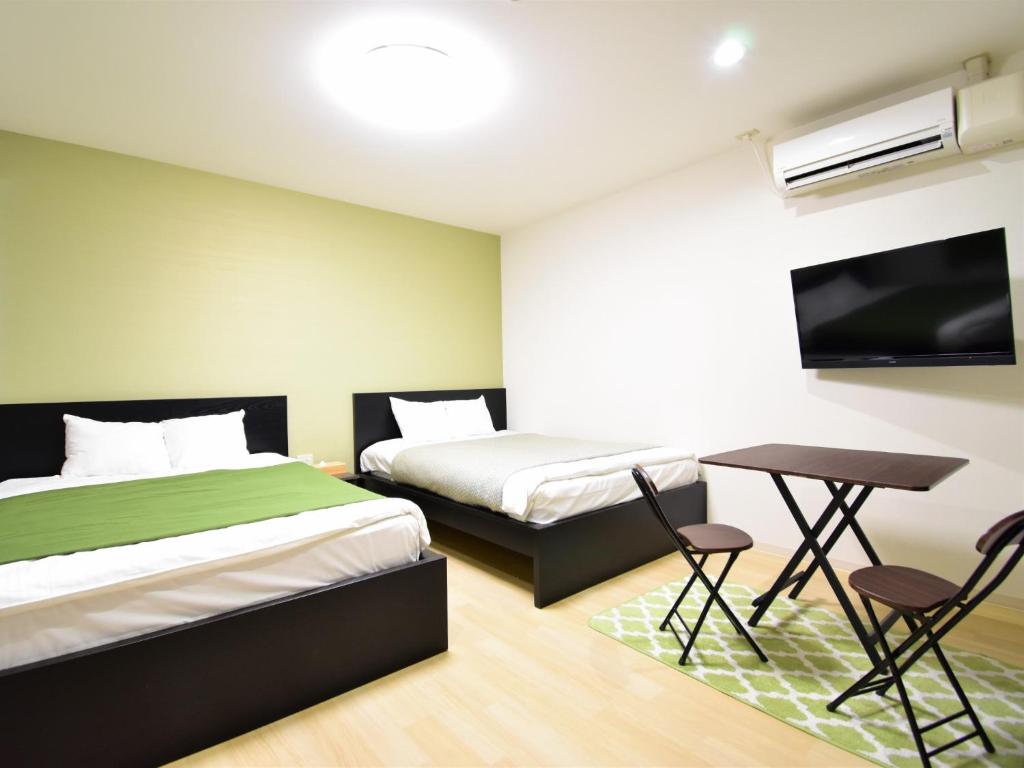 冈山Regariain - Vacation STAY 84627的一间卧室配有两张床、一张桌子和一台电视。