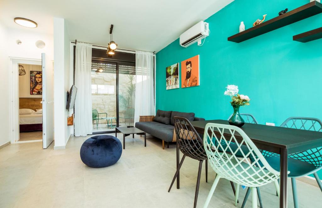 贝尔谢巴הרצל בוטיק מבית דומוס - Herzl Boutique Apartments by Domus的客厅设有蓝色的墙壁和桌椅