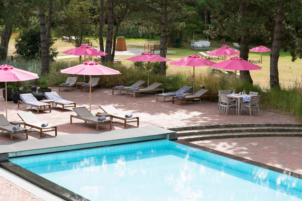 圣彼得奥尔丁阿勒尔福斯Spa酒店的一个带桌椅和粉红色遮阳伞的游泳池