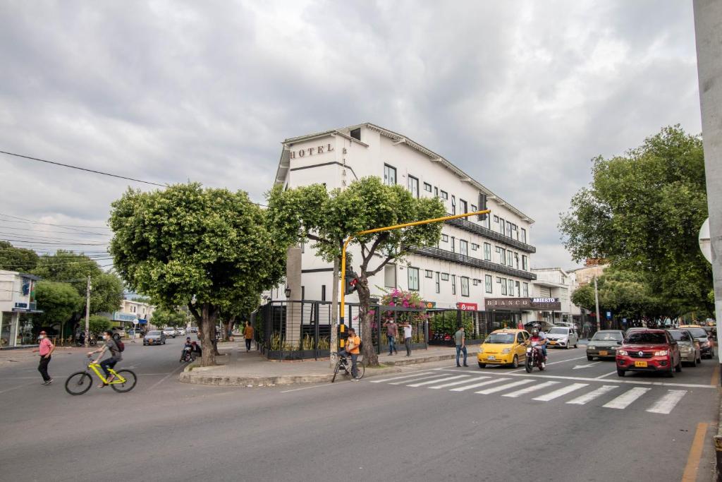 库库塔Bianco Hotel Boutique的一条有白色建筑的街道,人们骑着自行车和汽车