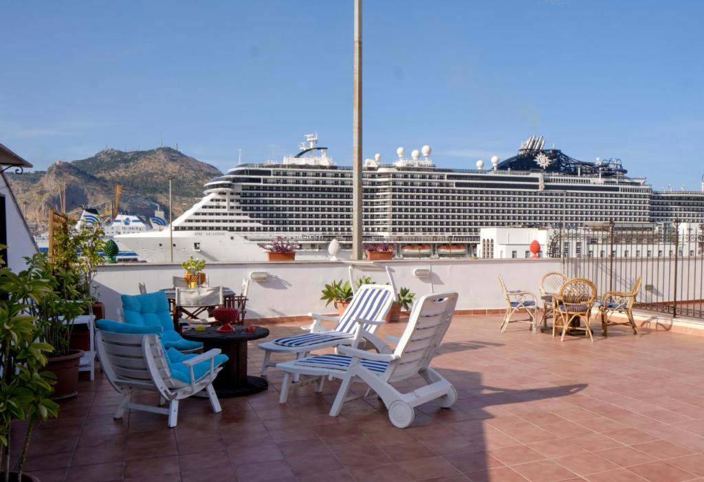 巴勒莫Attico con terrazza sul porto的阳台配有椅子和一艘背景游轮